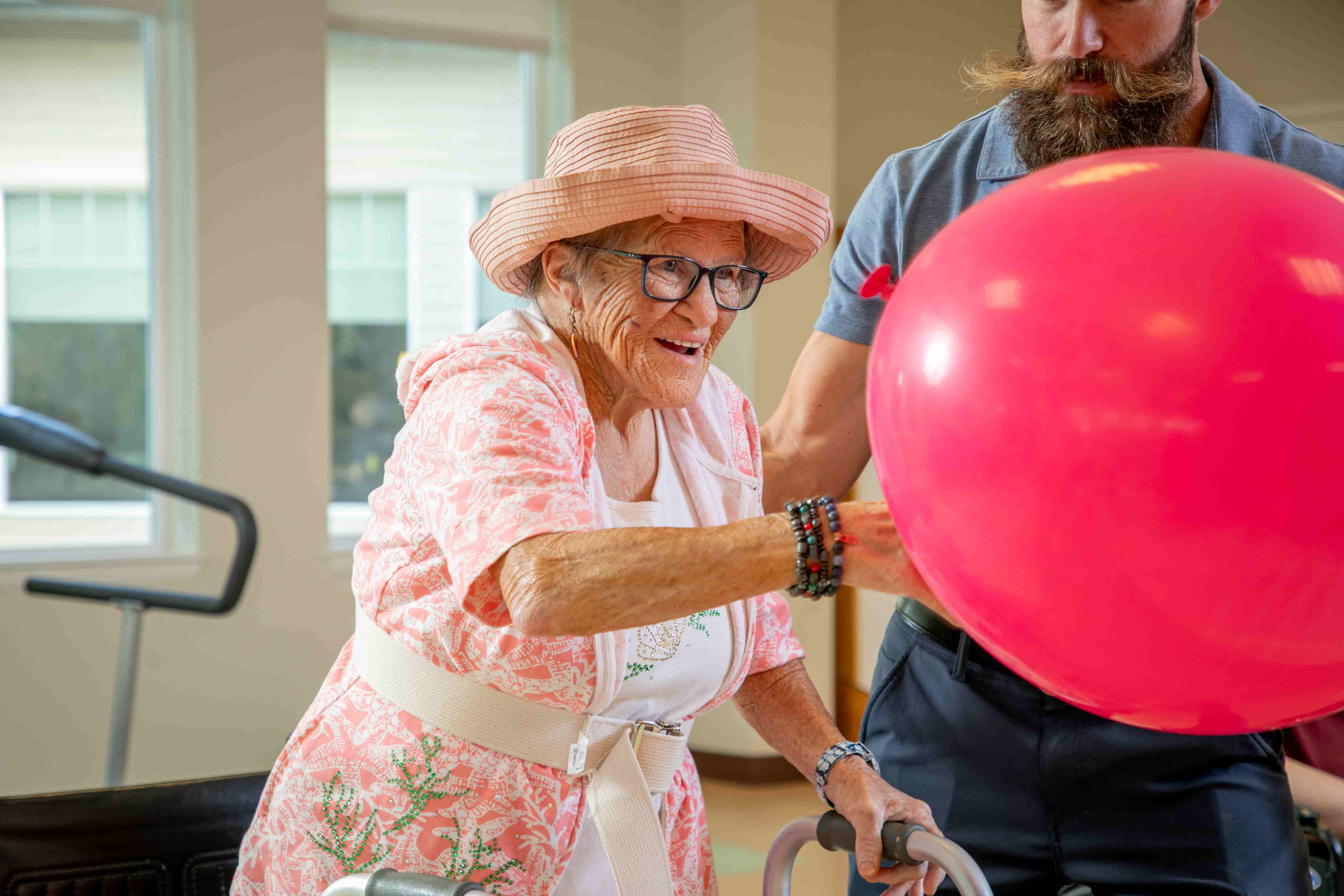 female senior hitting pink therapy balloon