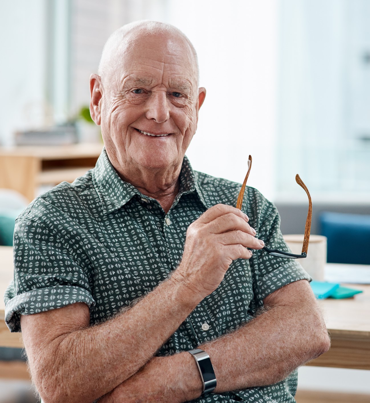 Man with arms crossed holding a pair of glasses