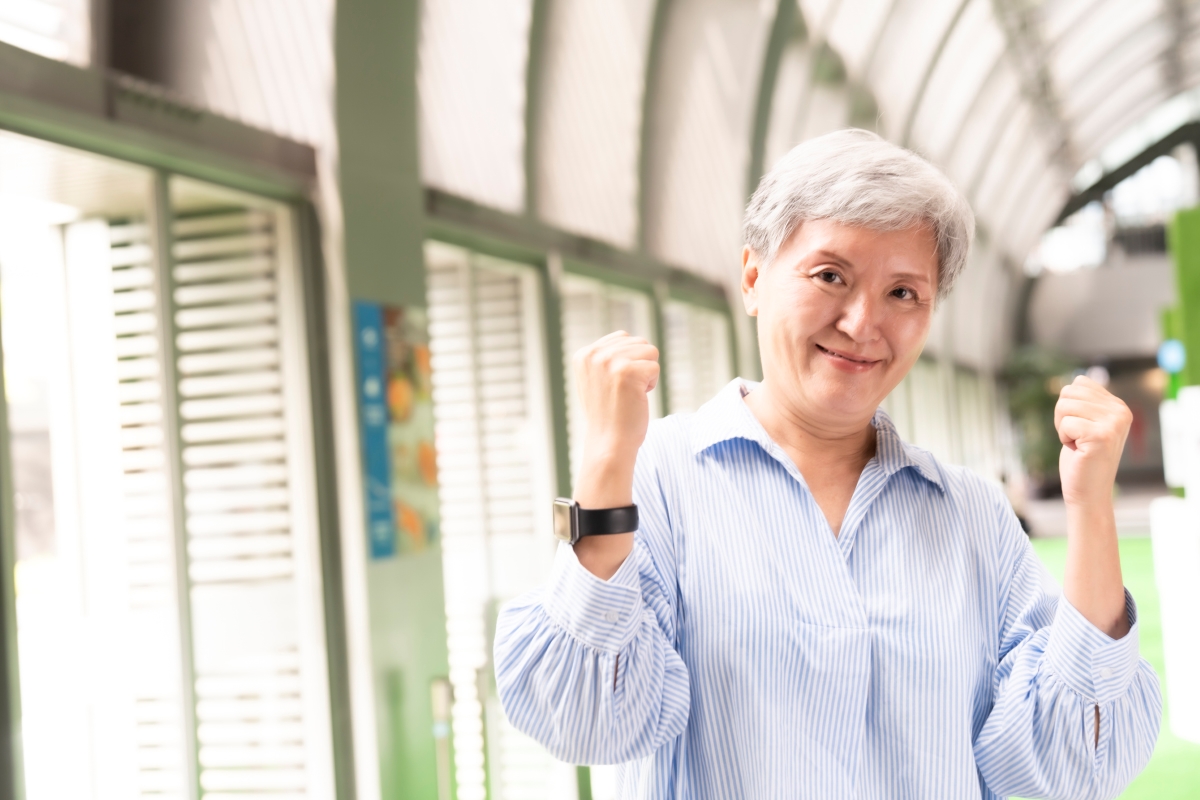 older female smiling with arms up