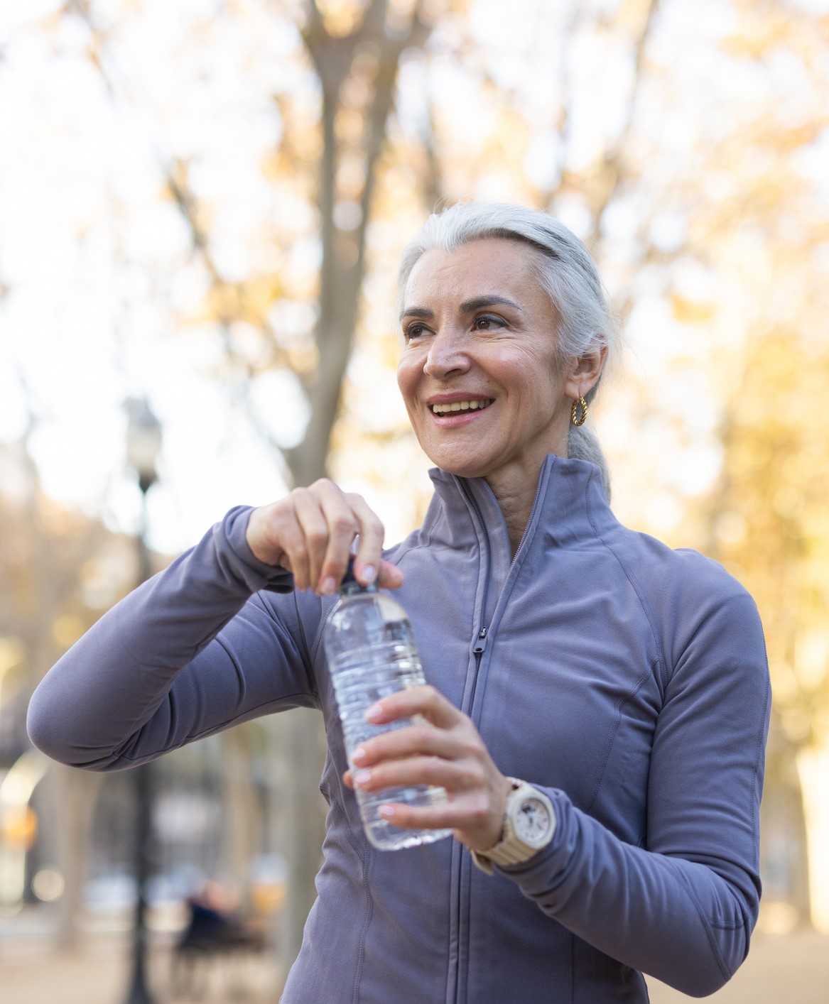 Woman outside opening a water bottle