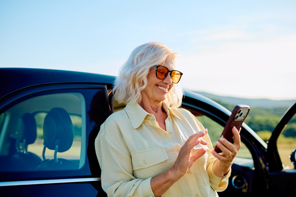 older female outside car looking at phone
